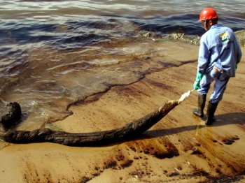 Funcionário da Petrobras duante o trabalho de remoção do óleo. (Foto: Reginaldo Pupo/ Estadão Conteúdo)